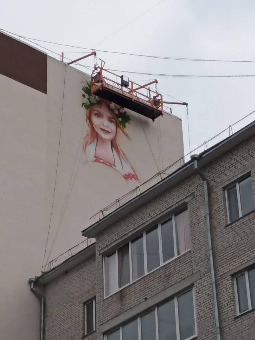 Новини Хмельницького - фото з У Хмельницькому малюють нові мурали: що про них відомо (ФОТО) На зображенні може бути: 1 особа, небо та цегляна стіна