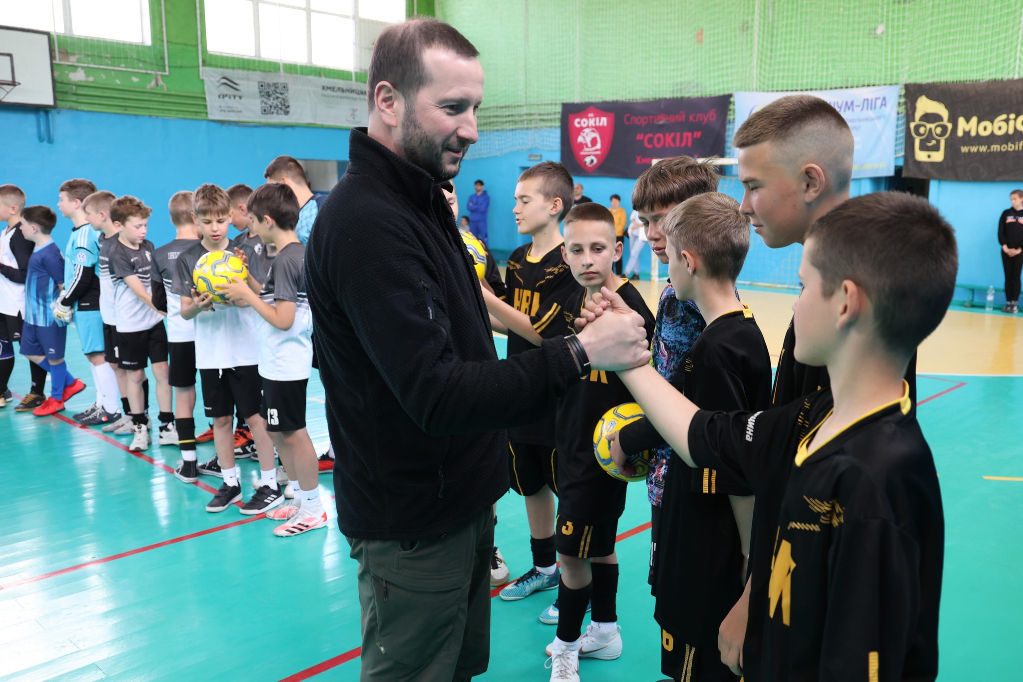 На зображенні може бути: 10 людей, люди грають у волейбол, люди грають у баскетбол, гравці в футбол та текст «1 КМЕЛьНиц СОЙл Спорт ТаРний Спортнийклуб клуб "СОКИЛ" УМ-ЛАГА Моб. www.mobil nobi www CSp HCU 3 еннт»