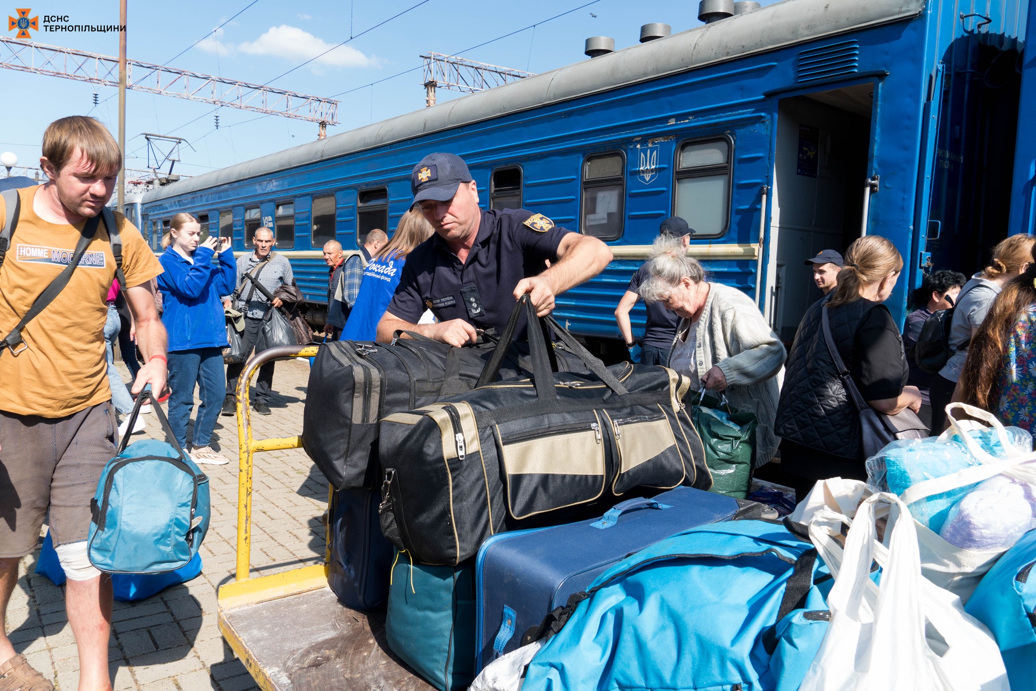 На зображенні може бути: 10 людей, турнікет, валіза, потяг та текст