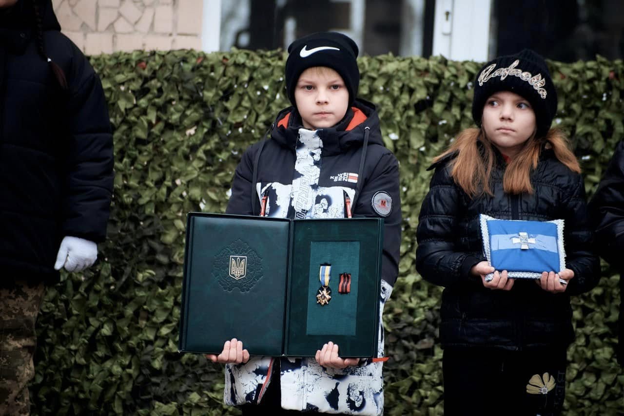 Новини Хмельницького - фото з У Кам’янці відкрили меморіальну дошку загиблому військовому – Денису Дорофєєву Возможно, это изображение 3 человека, ребенок, пуховик и текст